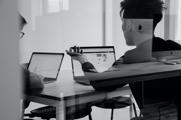 two people sitting at a table with open laptop 